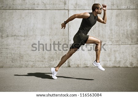 sport man starting running. Young man jogging front cement wall Royalty-Free Stock Photo #116563084