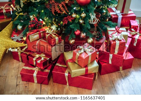 Christmas Gifts wrapped in classic red paper, background with xmas lights bokeh of blurred under Christmas tree. Copy space Royalty-Free Stock Photo #1165637401