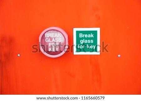 Break glass for key sign and container fixed to orange background wall for emergency
