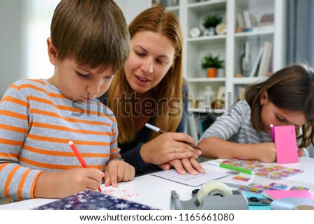 Mother together with kids at home writing birthday cards. Early education