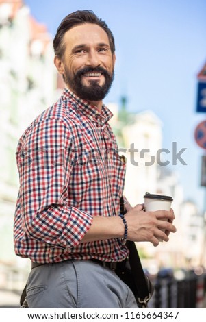 Pleasant walk. Cheerful adult man smiling while going to work along the street
