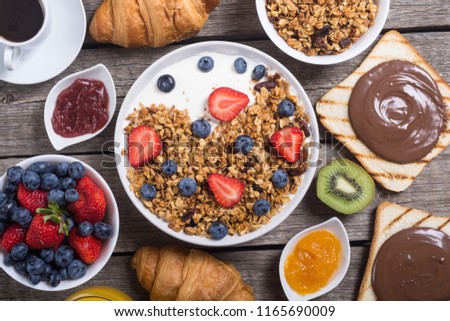 Healthy breakfast . Granola yogurt and berries , juice , jam and coffee