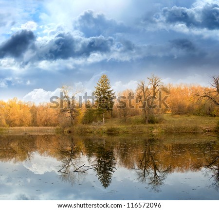 Autumn landscape against the terrible sky and the river
