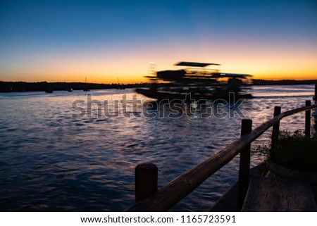 Ferry crossing the river during sunset. Long exposure photography. The sun has already crossed the horizon.