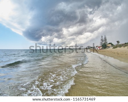 Magnificent sunny and cloudy mixed sky above a seaside place named "Granelli Beach", in the southern Sicily. The shot is taken during a beautiful sunny day, while a storm is coming.