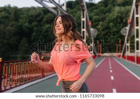 Carefree white girl in pink t-shirt running on nature background. Outdoor photo of graceful european lady training in morning.