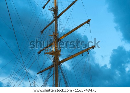The mast of a large sailing ship against the background of the evening sky.