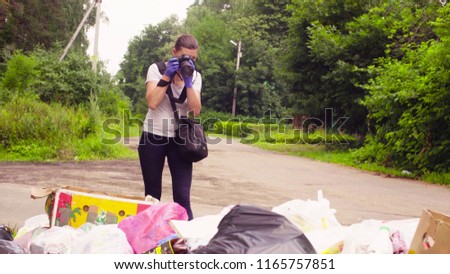 Woman scientist environmentalist making photos of garbage dump.