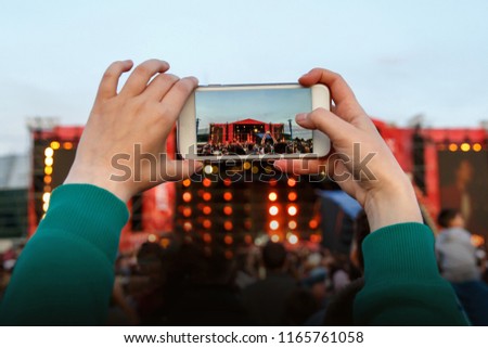Women take a picture with mobile phone at music festival