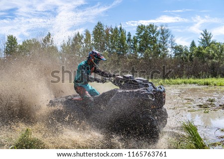 ATV Quad polaris rides fast on big dirt and makes splashes of dirty water