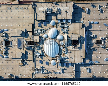 The shopping center roof, top view srtictly above - construction of roof equipment with antennas, ventilation outlets and other roof installation. View from drone at summer day