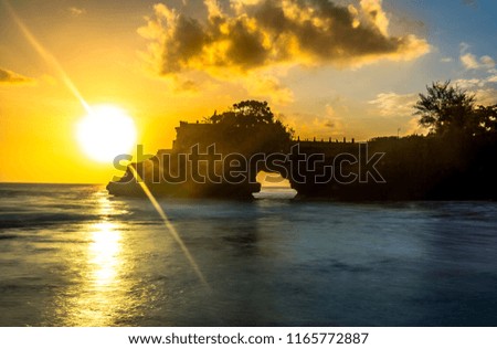 Beautiful colorful  sunset view look through arch rock below Pura Batu Bolong  in Bali island of Indonesia.