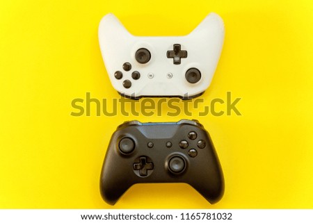 White and black two joystick gamepad, game console on yellow colourful trendy modern fashion pin-up background. Computer gaming competition videogame control confrontation concept