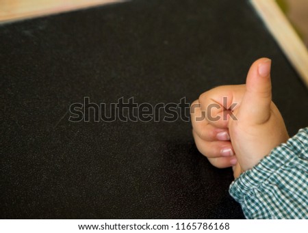 student hand making ok detail on a blackboard