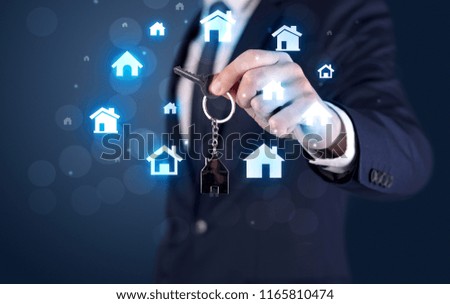 Businessman in suit holding keys with house graphics around and dark background
