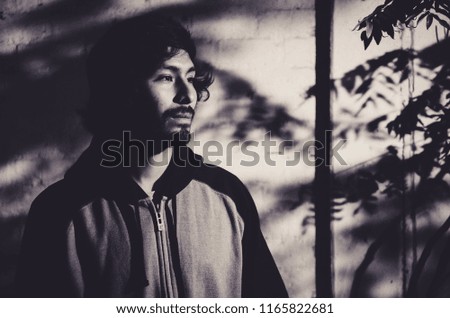 Portrait of young man with beard wearing shirt and shades of trees in the park