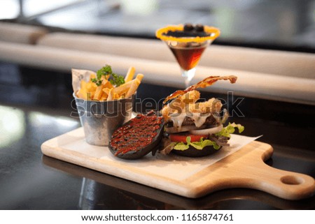 Black burger with beef and cheese and french fries isolated .