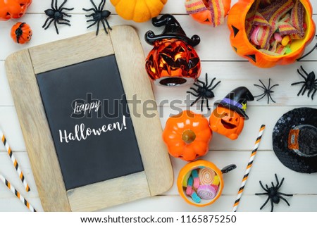 Table top view aerial image of decoration Happy Halloween day background concept.Flat lay accessories essential object to party the pumpkin & candy dessert on white wooden.Text of season on blackboard
