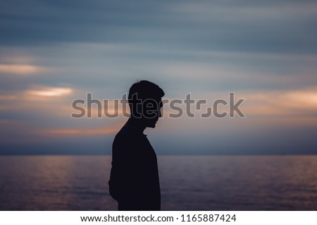 Silhouette of a lonely man standing at the sea with twilight sky background.Copy space on above. Concept for show Lonely moment, need somebody to talk about everything.Or waiting for a pointless.
