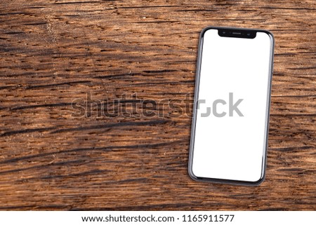 Smartphone lies on a wooden table. Isolated white screen with copy space.