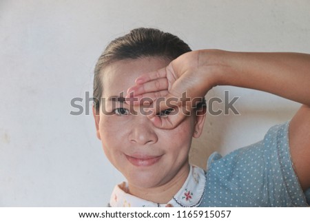 woman with happy face smiling doing sign with hand on eye looking through fingers.