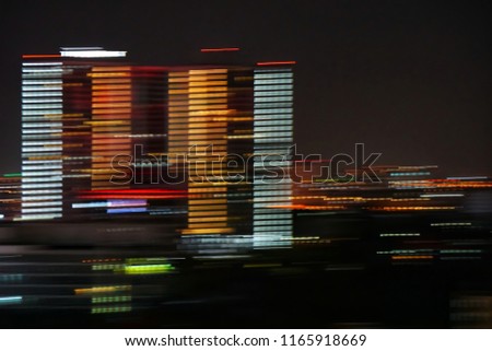 motion blurred and effects of multi colored neon on high building (cityscape) in dark night
