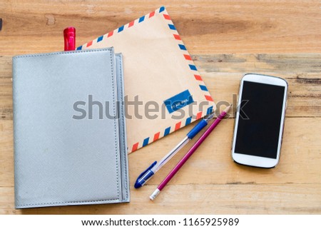 envelope air mail  letter confidential papers ,notebook planner and mobile phone for business at office desk