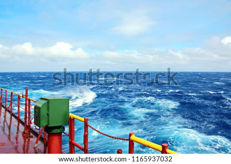 Storm waves in the world ocean. Kind of waves, crests, splashes, foam against the background of the sea horizon and the blue sky and clouds. A view of storm waves from the ship's side.