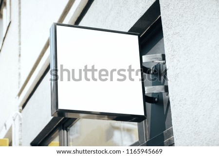 Empty square white billboard on building with classical architecture and daylight. Mock up 