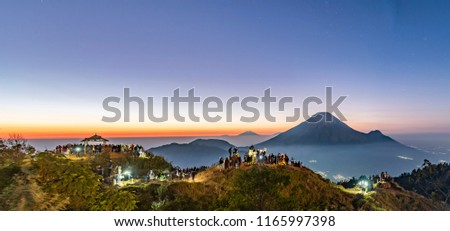 Sundoro volcano view before sunrise with people chasing the light and misty horizon background in Dieng Plateau of Indonesia