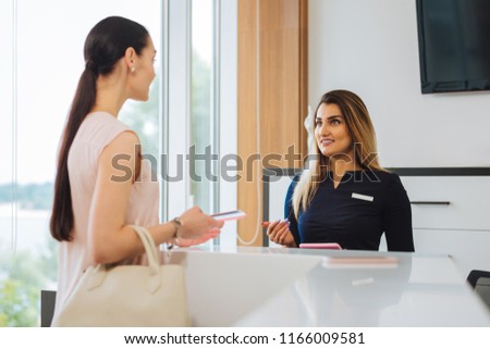I have an appointment. Nice pleasant woman talking to the receptionist while having an appointment in the beauty salon Royalty-Free Stock Photo #1166009581
