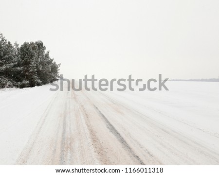 picture of the road in the winter season. Close-up, on the snow-covered asphalt stripes visible from the tires of the car