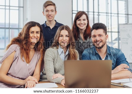 Successful young business team posing for a portrait together at an office table smiling at the camera with three women and two men