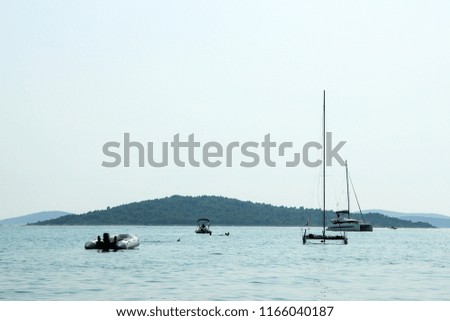 A picture of several boats floating on the blue ocean during the hot summer day. Relaxing vacation activity for the people. 