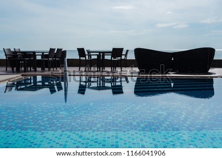 The edge Luxury swimming pool with black fashion deckchairs on the beach.