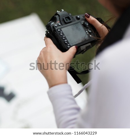 Female hands hold a professional camera. Photographer blogger makes a photo