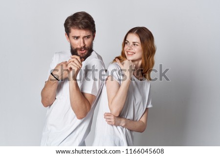 woman and man in light T-shirts on a gray background emotions                               