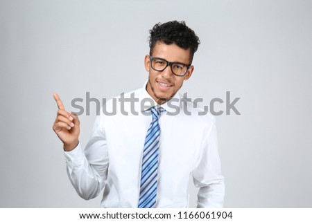 Handsome African-American businessman pointing at something on grey background