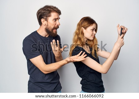man and woman in dark T-shirts looking at the phone in gray background                       