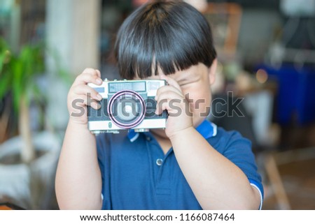 A boy is taking a Photo film camera in the coffee cafe.