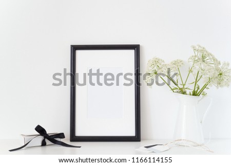 Black portrait frame a4 mock up with a Aegopodium podagraria in wight jug and present box. Mockup for quote, promotion, headline, design. Template for small businesses, lifestyle bloggers, social