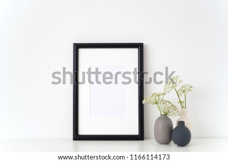 Black portrait frame mock up with a summer Aegopodium podagraria in little vases gray, white and black. Mockup for quote. Template for small businesses, lifestyle bloggers, social media