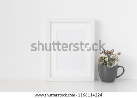White A5 portrait frame mockup with small bouquet of dried flowers in gray mug on white wall background. Empty frame, poster mock up for presentation design. Template frame for text, lettering, modern