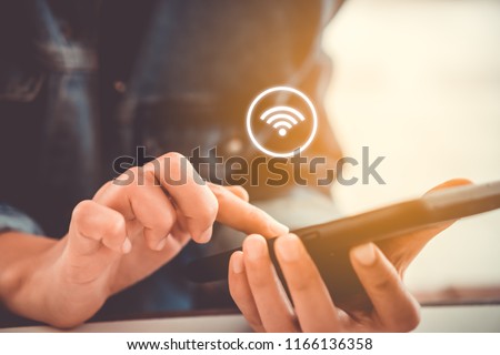 Woman hand using smartphone with wifi icon in cafe shop background. Business communication social network concept. Royalty-Free Stock Photo #1166136358