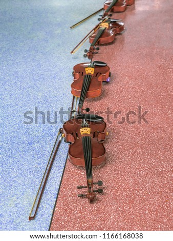 Violin on the cement  floor colour red and green. Many violins for students to play at the school.