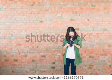 Asian photographer women with digital DSLR camera on brick wall outdor activity