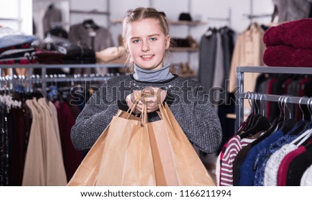 Happy girl holding many bags after shopping in modern clothing store
