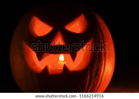 Orange mad pumpkin as head of Jack-o-lantern with carved eyes and wicked smirk. Scary symbol of Halloween. Gourd on the left side.