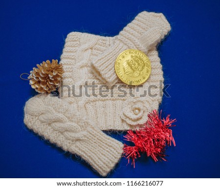 Knitted wool baby hat and mittens on blue background. Translation. happy New Year