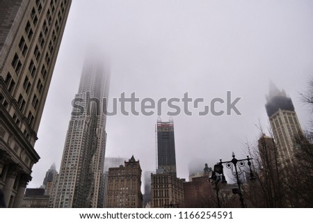 A cityscape, both old and modern styles buildings are built around a city in a foggy day.
A mist is covered all over buildings' top.
A winter mist, city view.